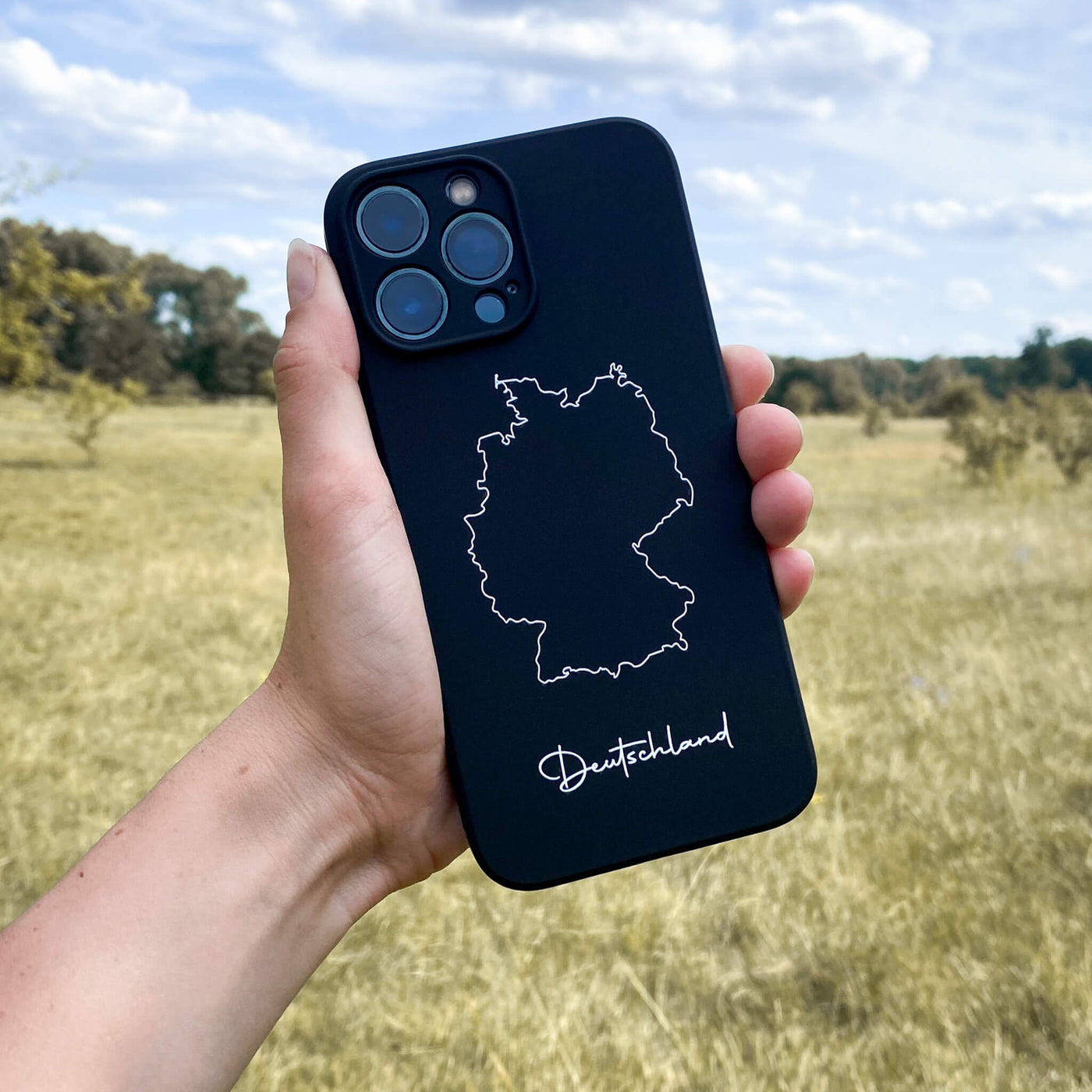 Deutschland Handyhülle in der Hand vor einer Wiese