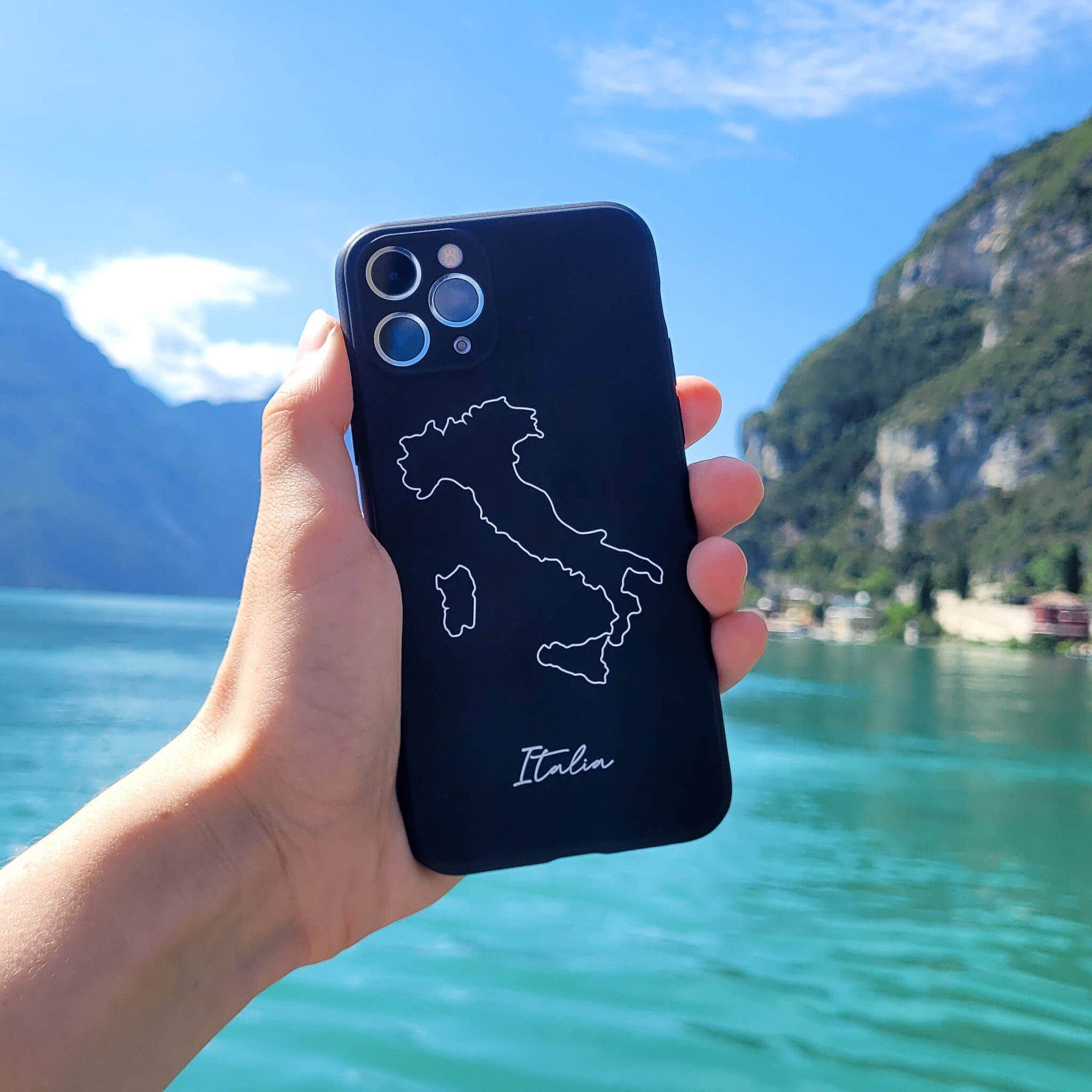 Italien Handyhülle in der Hand vor einem türkisfarbenen See mit Felswänden