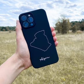 Algeria phone case held in the hand in front of a meadow