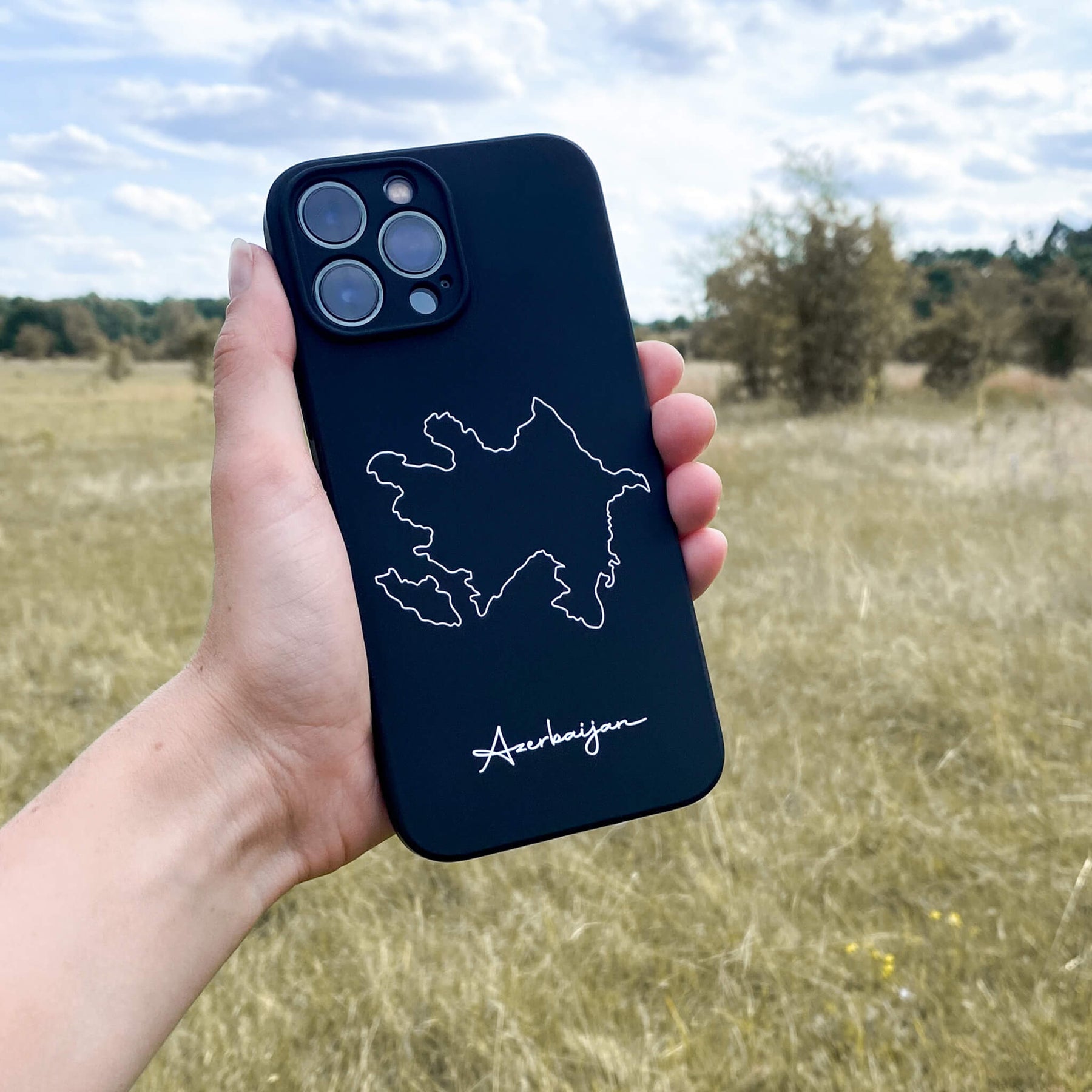 Azerbaijan phone case held in the hand in front of a meadow