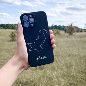 Pakistan phone case held in the hand in front of a meadow