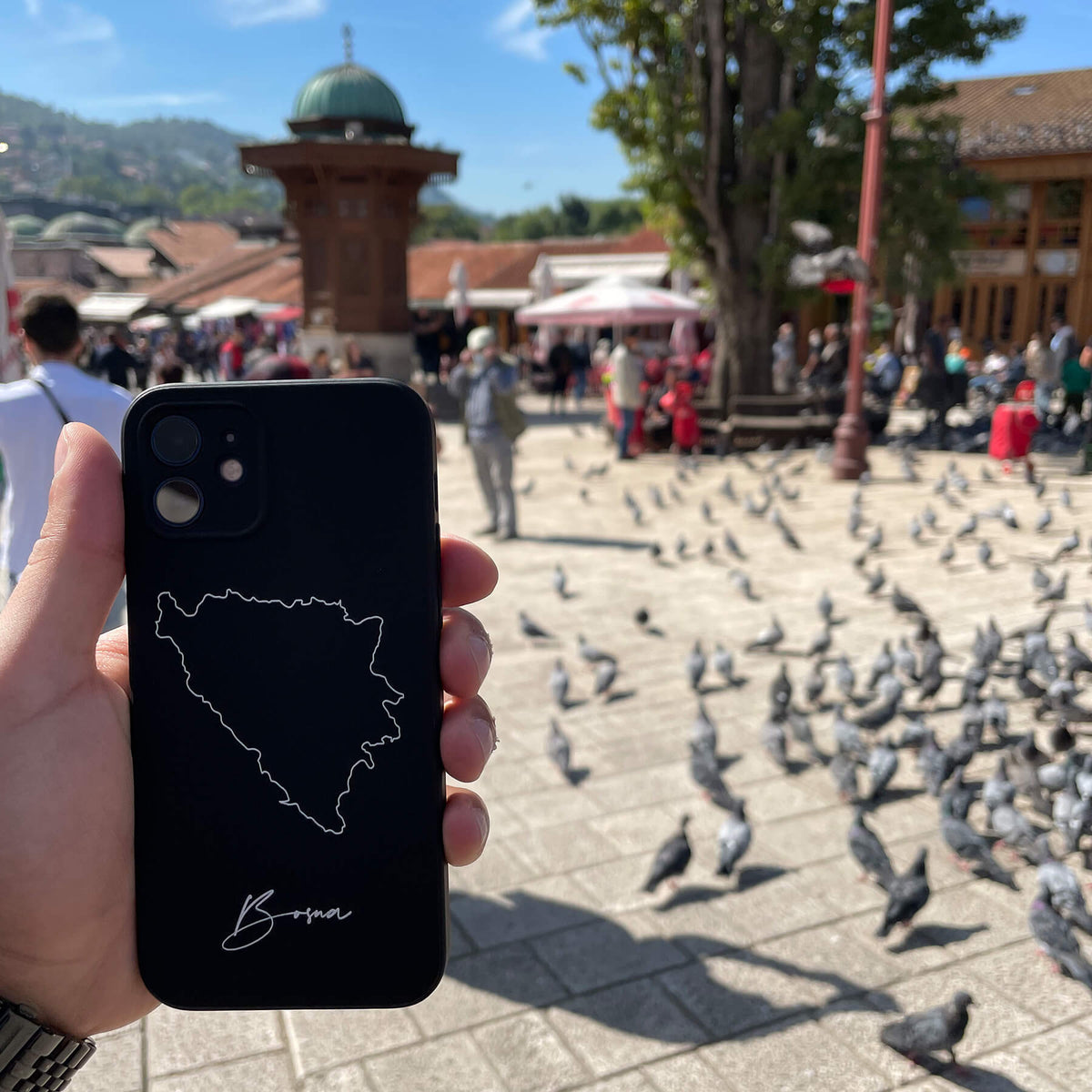 Bosnien Handyhülle in der Hand auf einem Platz mit Tauben in der Altstadt