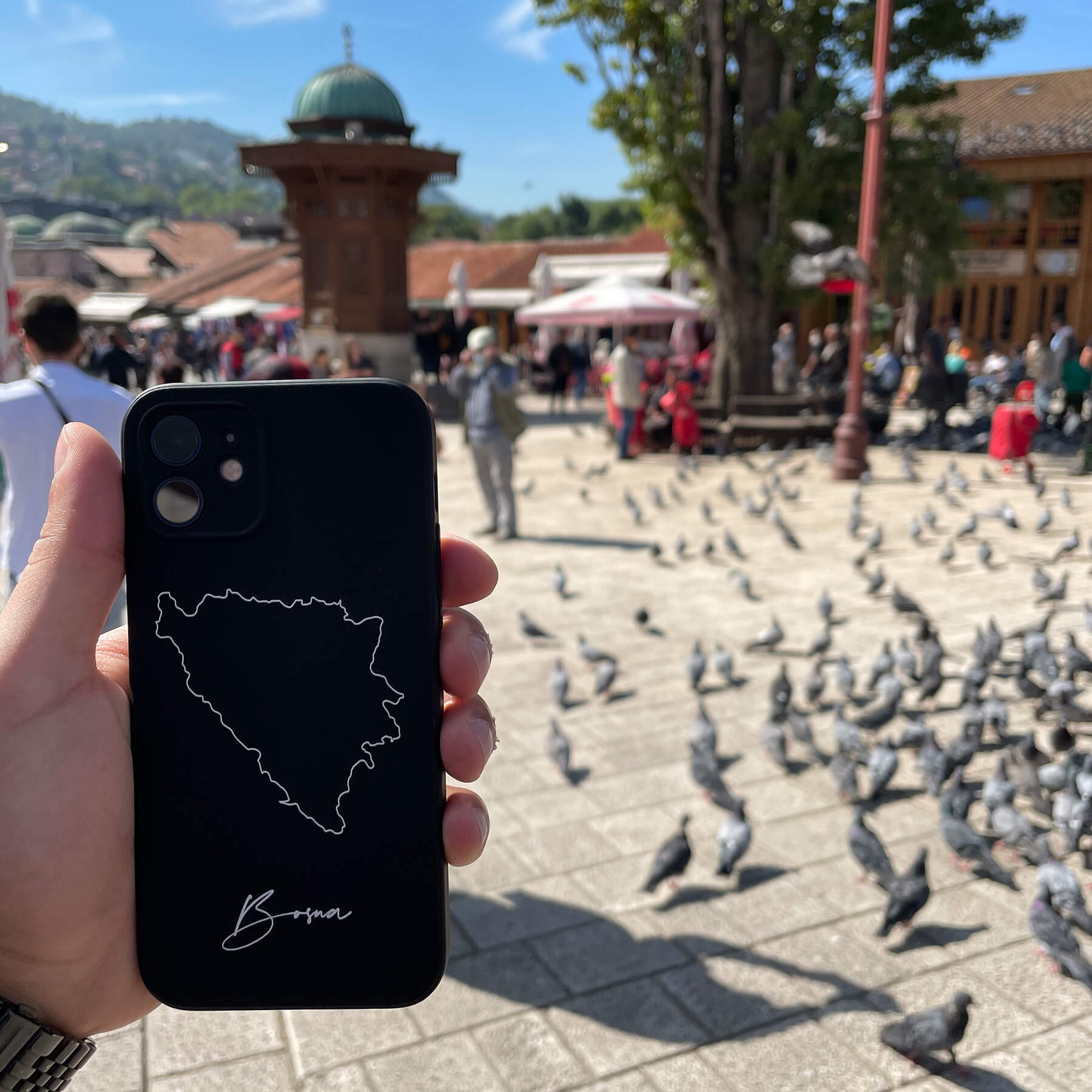 Bosnia phone case held in the hand on an old-town square with pigeons